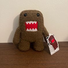 a brown stuffed animal with red teeth and big mouth sitting on top of a wooden table