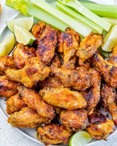 chicken wings with celery and lemon wedges on a white plate, ready to be eaten