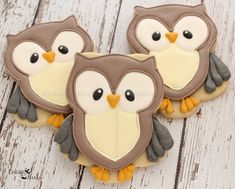 three decorated owl cookies sitting on top of a wooden table