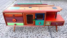 an old fashioned wooden tv stand with drawers and knobs on the sides, painted in different colors