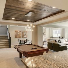 a pool table in the middle of a living room with stairs leading up to it