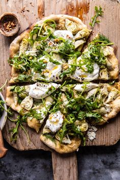 a pizza topped with lots of veggies on top of a wooden cutting board