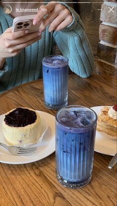 a woman taking a photo of a dessert on her cell phone at a table with two drinks