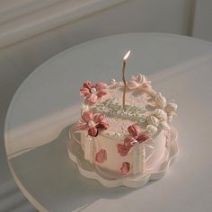 a white cake with pink flowers and a single candle