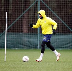 a man in yellow jacket kicking a soccer ball