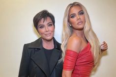 two barbie dolls standing next to each other in front of a white wall and one is wearing a red dress