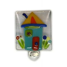 a glass bottle opener with a colorful house on it