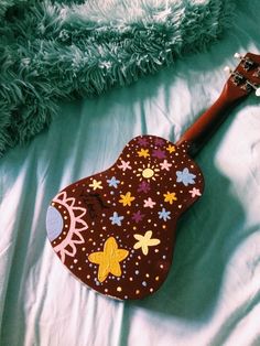 a wooden guitar shaped like a flowered heart laying on a bed with a green blanket