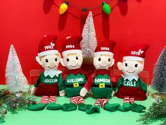 three elf dolls sitting next to each other in front of christmas decorations