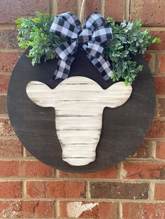 a black and white buffalo head hanging on a brick wall with greenery in the center