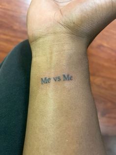 someone has a tattoo on their wrist that says me vs me and the word is written in blue ink