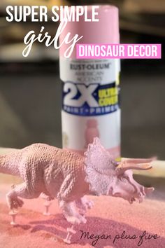 a small toy dinosaur on a table next to a bottle of glue with the text super simple girly dinosaur decor