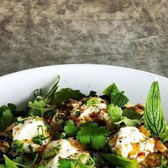 a white bowl filled with food and garnished with green leafy leaves on top