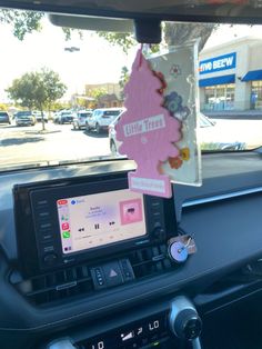 a car dashboard with an electronic device in the center and a little trees sticker on it