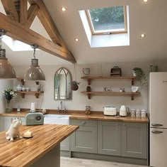 a kitchen with wooden counter tops and open shelving above the sink is lit by two pendant lights