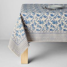 a blue and white table cloth with flowers on it, sitting on top of a wooden stand