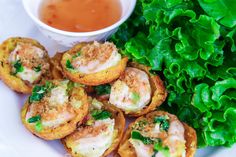 small appetizers on a plate next to greens and dipping sauce in a bowl