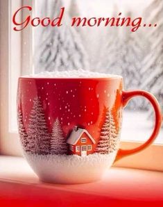 a red coffee cup sitting on top of a window sill next to snow covered trees