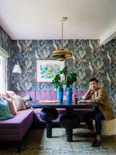 a man sitting at a table in front of a purple couch