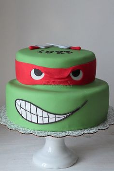 a green cake with a teenage mutant face on it's top and eyes painted on the side