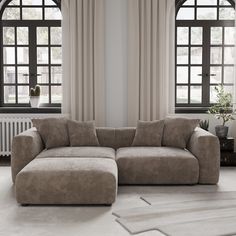 a large sectional couch in front of two windows