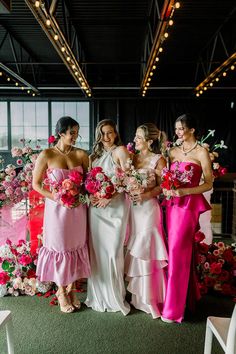 the bride and her bridesmaids are all dressed in different colored gowns, holding bouquets