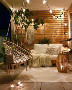 an outdoor living room with hanging plants and lights on the wall, along with a hammock chair