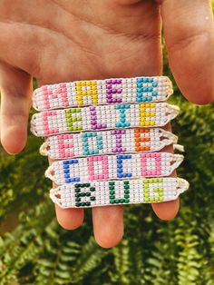 a person holding three bracelets with letters on them