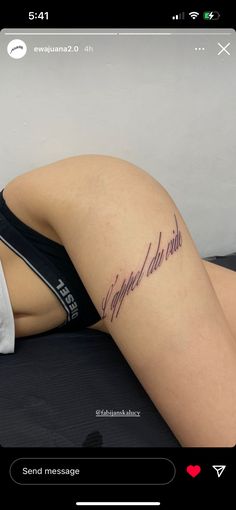 a woman with a tattoo on her thigh laying down and looking at the camera she is wearing