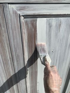 a person holding a paintbrush in front of a wooden door