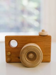 a small wooden camera sitting on top of a white table next to a glass window