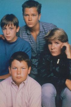 three young men sitting next to each other in front of a blue background with one man looking at the camera