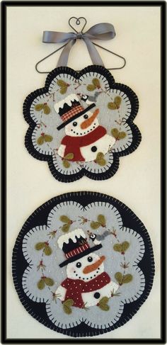 two snowmen with hats and scarfs are hanging on the wall