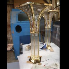 a gold colored table lamp sitting on top of a white cloth covered table next to a blue machine