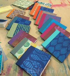 many different colored notebooks laid out on a table