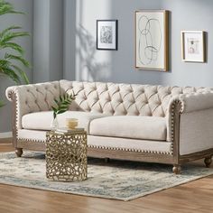 a living room scene with focus on the tufted couch and coffee table in the foreground