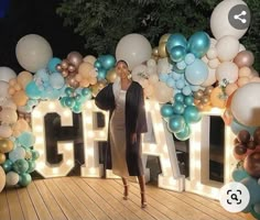 a woman is standing in front of balloons and letters that spell out the word chaos