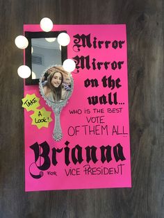 a mirror on the wall that has been decorated with pink paper and black lettering, along with an image of a woman's face