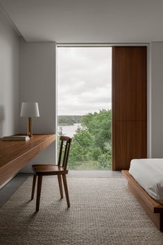 a bedroom with a bed, desk and chair in front of a large window overlooking the water