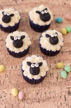 four cupcakes with white frosting and black sheep faces