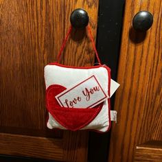 a red and white bag hanging from a wooden door with a tag on it that says i love you