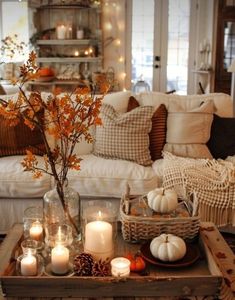 a living room filled with lots of white furniture and candles on top of a coffee table