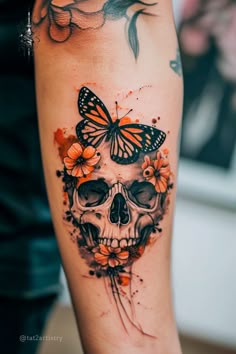 a woman's arm with a butterfly and skull tattoo on it