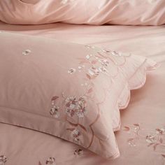 pink bedding with white flowers on it and two pillow cases in the background,