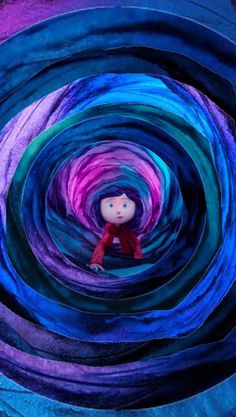 a doll is sitting in the middle of a colorful tunnel