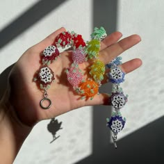 a person's hand holding several different colored beaded items in their left hand