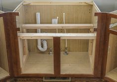 the inside of a wooden cabinet with pipes in it