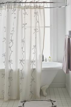 a white bath tub sitting next to a shower curtain in a bathroom under a window