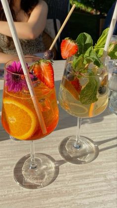 two glasses filled with drinks sitting on top of a table