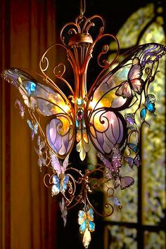 a butterfly chandelier hanging from the ceiling in front of a stained glass window